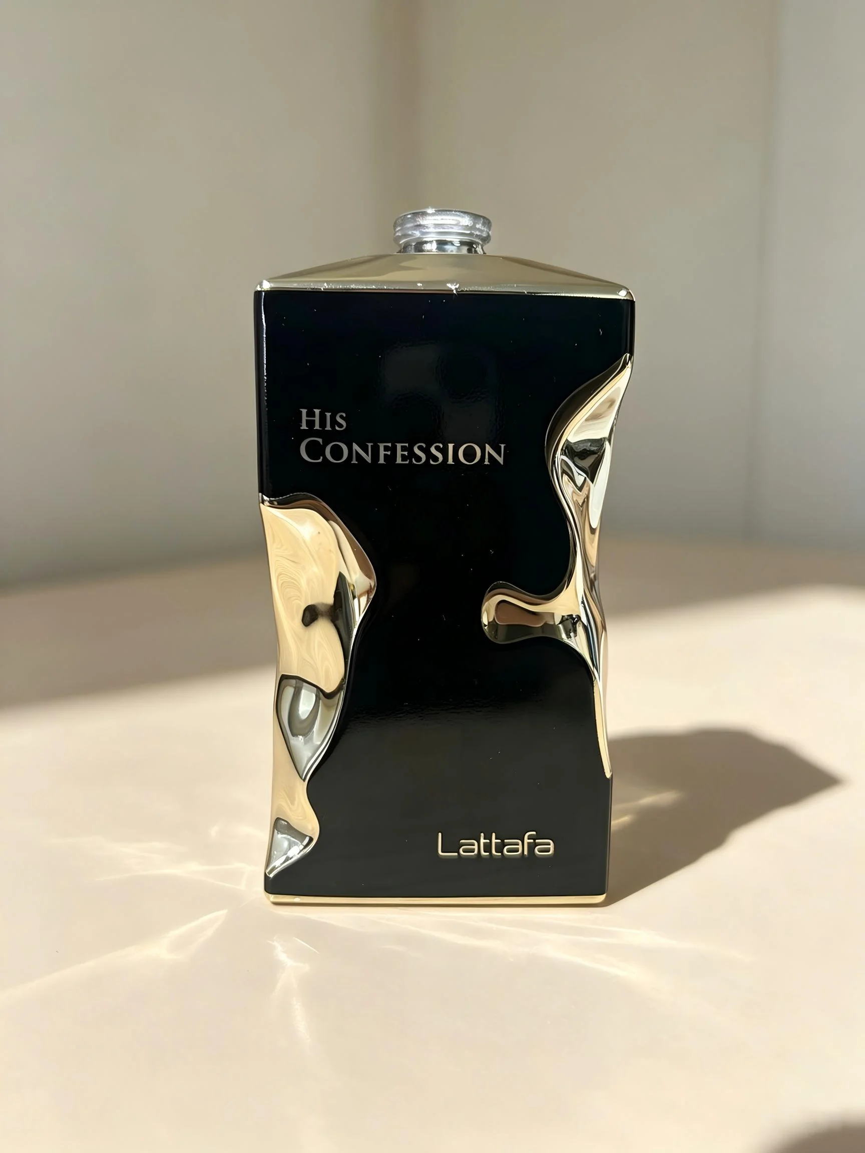 Black and gold rectangular perfume bottle with metallic wave decoration — sample